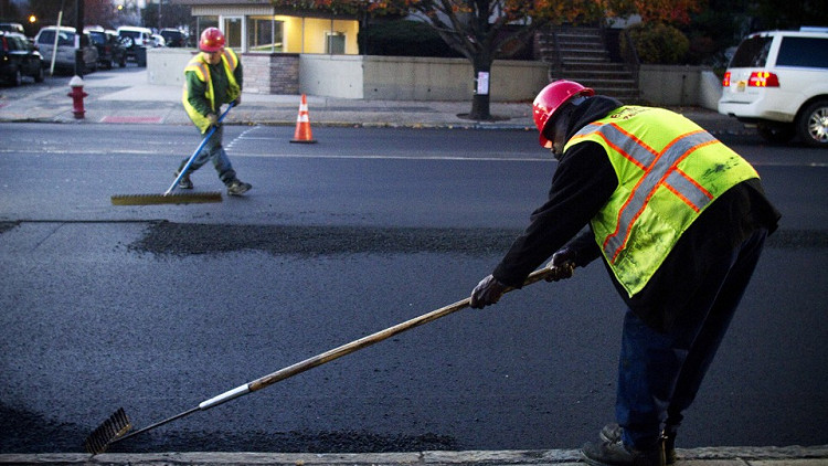 two road construction workers working on road asphalt